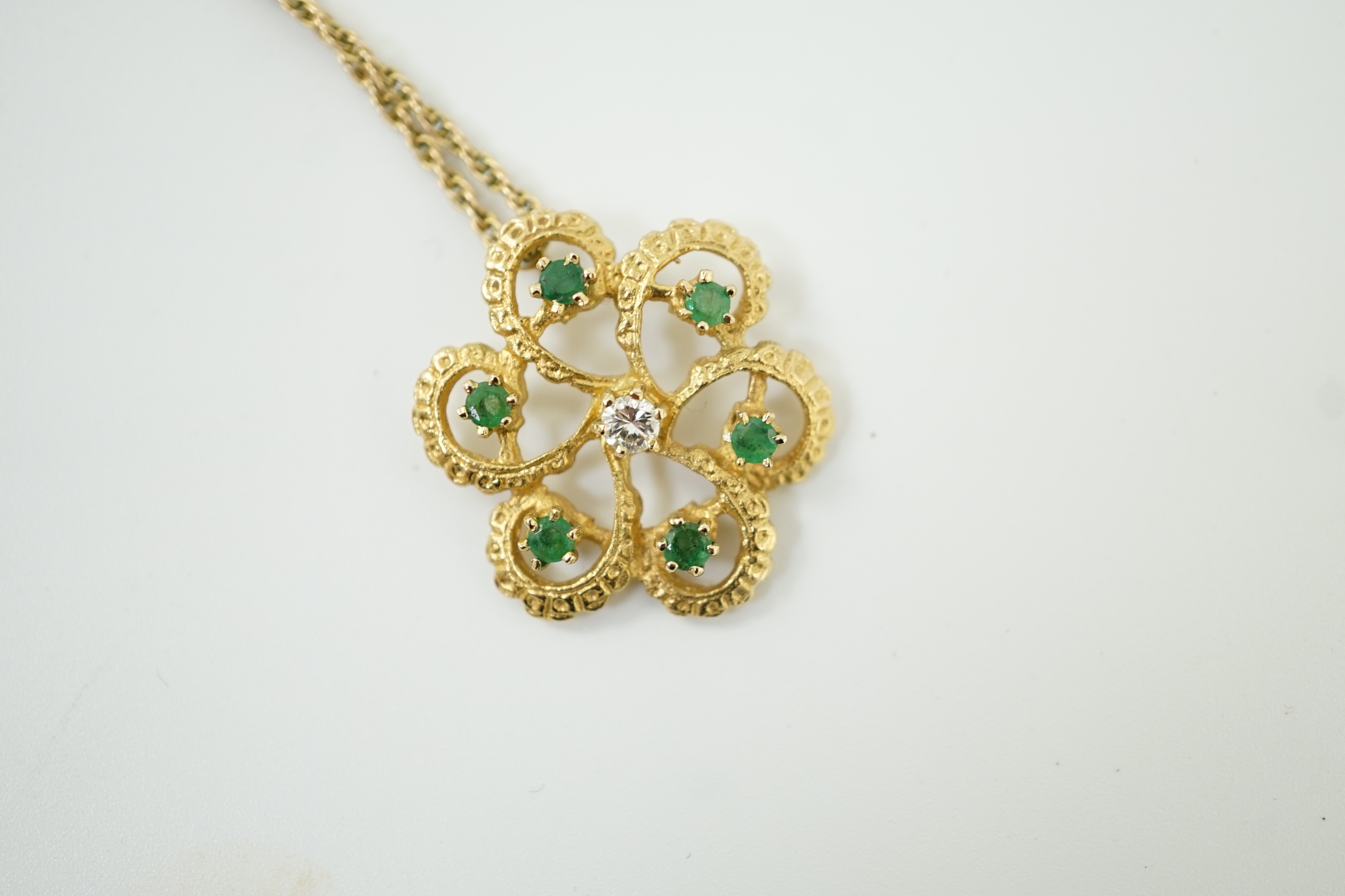 A modern yellow metal, emerald and diamond set stylised flower head pendant, 25mm, on a 375 chain, 46cm, gross weight 6.7 grams.